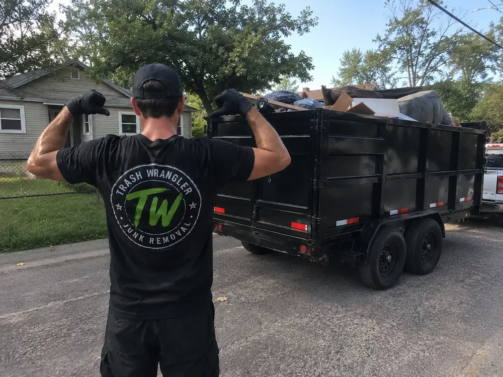 Casey, owner of Trash Wrangler Junk Removal, standing beside a fully loaded dump trailer after a junk removal job in the Oklahoma City metro